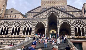 People sitting on the steps of a cathedral with a detailed facade.