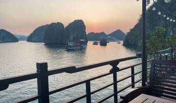 Sunset view of Halong Bay with boats on the water.