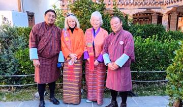 Four people in colorful traditional Bhutanese clothing posing outdoors.