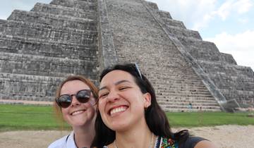 Two women taking a selfie in front of an ancient stone pyramid.
