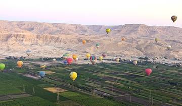A landscape with hot air balloons scattered above fields.