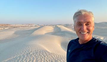 Man smiling with sand dunes in the background.