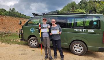 Two people holding certificates in front of a tourist van.