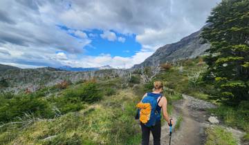 Hiker walking along a scenic trail surrounded by mountains.