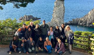 Group photo by the sea with a rocky island in the background.