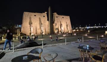 People visiting the illuminated Luxor Temple at night.