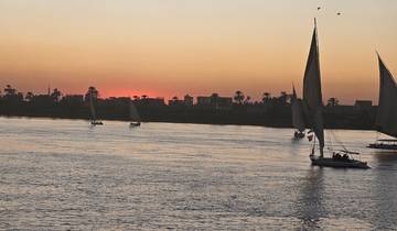 Feluccas sailing on the Nile River at sunset.