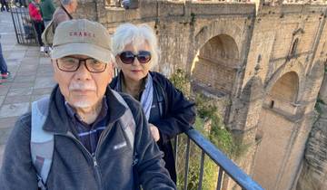 Elderly couple in front of a large stone bridge.