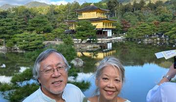 Couple in front of golden pavilion by a pond.