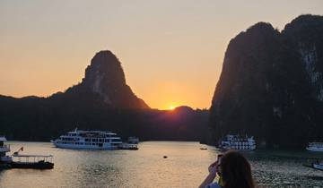 A sunset view of limestone karsts with boats on the water.