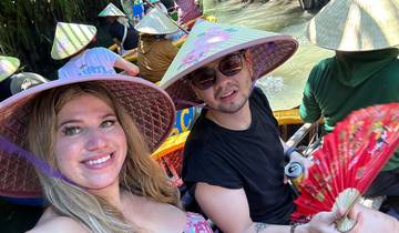 A group of people in a boat with traditional hats rowing through a canal.