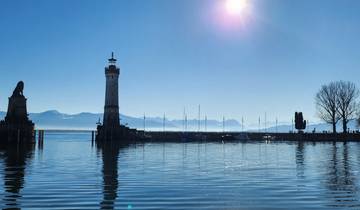 Harbor scene with lighthouse and distant mountains.