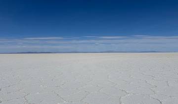 Expansive view of the Uyuni Salt Flats under a clear blue sky.