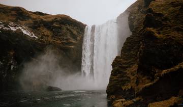 Tall waterfall surrounded by rocky cliffs and mist.