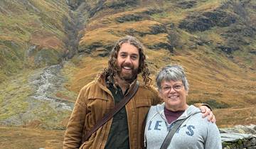 Two people standing in a scenic mountain landscape.