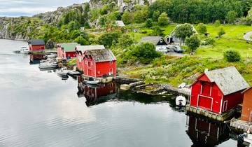 Scenic view of red cottages by the water reflecting in the still water.
