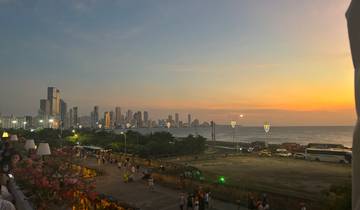 Seaside cityscape with tall buildings and a sunset sky.