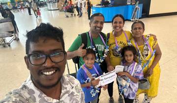 A smiling family group being welcomed at an airport.