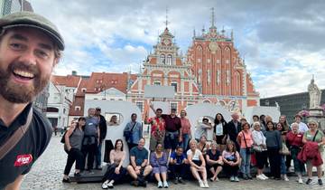 Large group of people posing in front of a historic building.