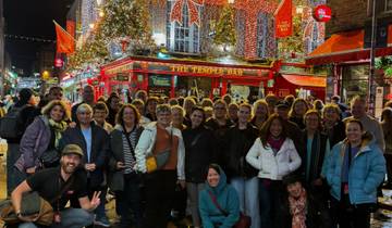 Large group of people posing in front of a famous bar with festive lighting.
