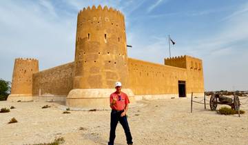 Historic fort with a person posing in front, and a flag on top.