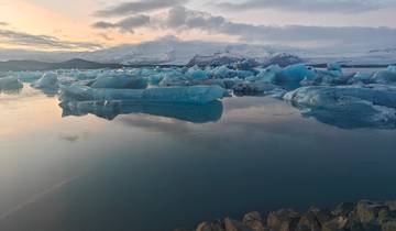 Icebergs floating on a glacial lagoon against a mountain backdrop.