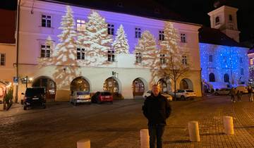 Illuminated building at night with people and cars.