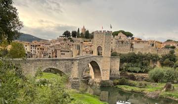 Historic stone bridge over a river leading to a village.