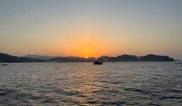 Sunset over a body of water with a boat silhouetted in the foreground.