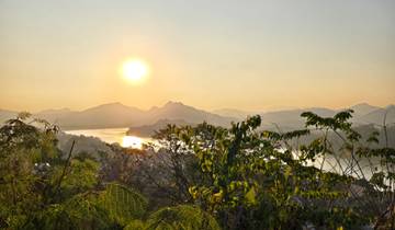 Sun shining over a river with mountainous terrain in the distance.