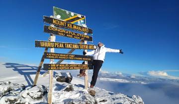 Person posing with a sign on Mount Kilimanjaro.
