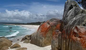 Red rocks and white sand beach with ocean waves.