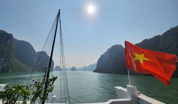 Vietnam flag flying on a boat in a bay with limestone karsts.