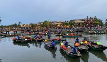 Busy river with boats and people, vibrant town in the background.