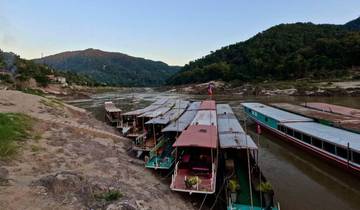 Boats lined up along a riverbank at sunset.