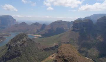 Panoramic view of a mountain range with valleys and a lake.