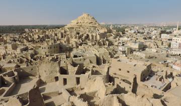 Ruins of an ancient fortress with a pyramid-shaped hill in the background.