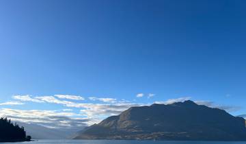 Mountain peak under a blue sky with clouds at the horizon.
