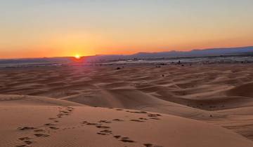 Sunset over vast sand dunes in the desert.