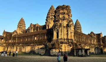 Ancient Angkor Wat temple with tourists walking around.