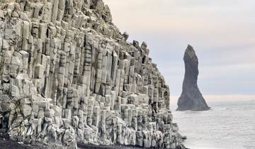 Rocky coastal landscape with basalt columns and an oceanic stack.