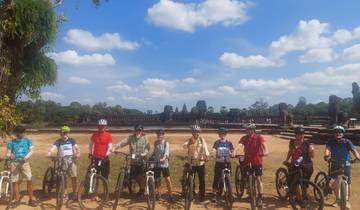 Group of cyclists in front of ancient temple ruins.