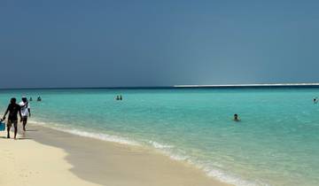 People enjoying a beautiful sandy beach with turquoise water.