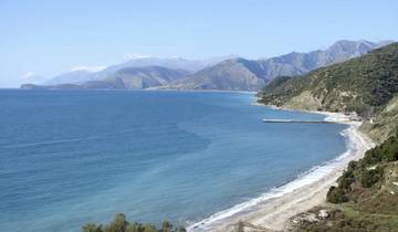 Coastal area with a curve of sandy beach and hills.