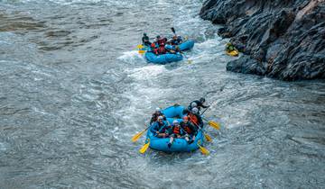 Multiple rafts with people paddling on a river.