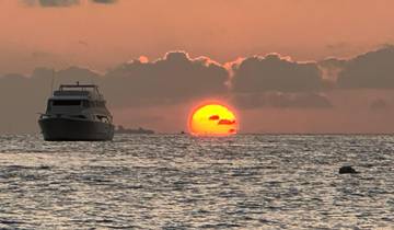 Boat on the ocean with a sunset in the background.