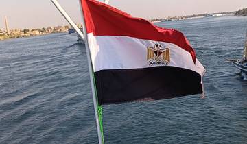 Egyptian flag waving on a ship with a river scene.