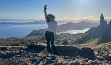 Person posing on a hilltop with a scenic view.