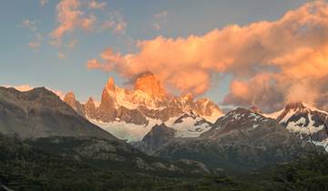 Sunlit mountain peaks with clouds at sunset.
