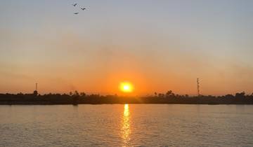 Sunset over the Nile River with birds in flight.
